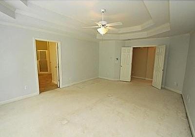 carpeted empty room featuring a raised ceiling and ceiling fan