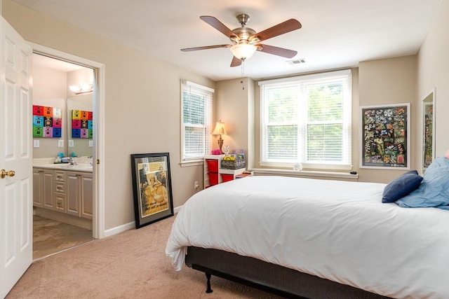 bedroom with ceiling fan, sink, light carpet, and ensuite bath