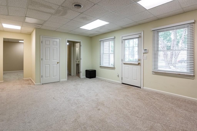 interior space with a drop ceiling and light colored carpet