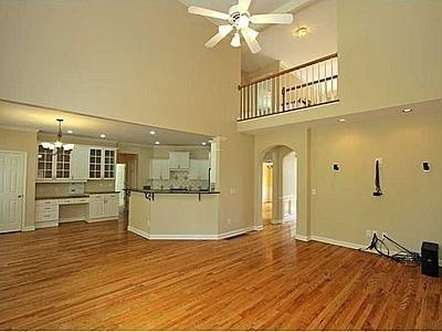 unfurnished living room featuring hardwood / wood-style floors, ceiling fan with notable chandelier, and a towering ceiling