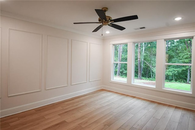 unfurnished room with a decorative wall, plenty of natural light, visible vents, and light wood finished floors