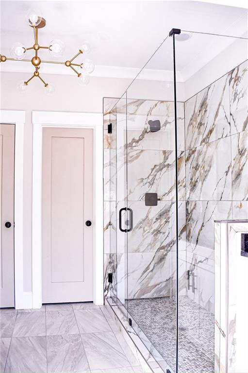 full bathroom with a marble finish shower, marble finish floor, and ornamental molding