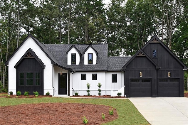 modern farmhouse style home with roof with shingles, board and batten siding, a front yard, concrete driveway, and an attached garage