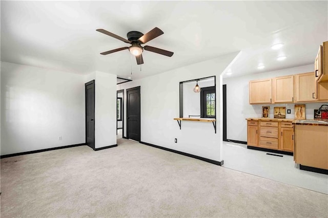 interior space featuring light carpet, baseboards, a sink, and ceiling fan