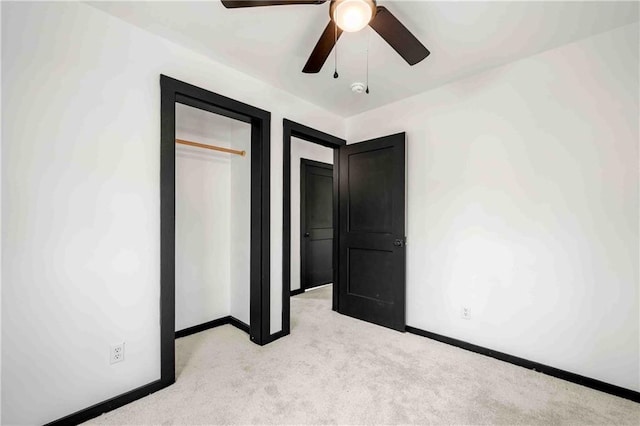 unfurnished bedroom featuring a closet, baseboards, a ceiling fan, and light carpet