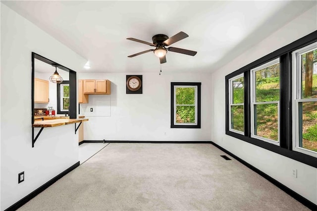 empty room with visible vents, light colored carpet, baseboards, and ceiling fan