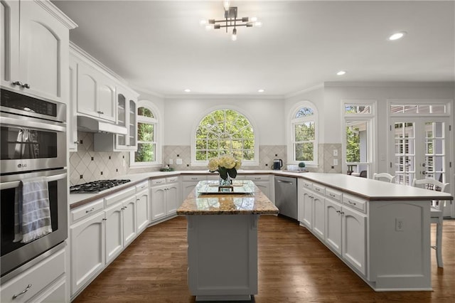 3260 Kingshouse Commons, Johns Creek, GA 30022 - kitchen with appliances with stainless steel finishes, a peninsula, a kitchen bar, white cabinetry, and ornamental molding