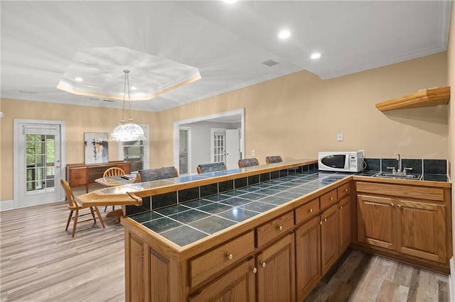 3260 Kingshouse Commons, Johns Creek, GA 30022 - kitchen featuring white microwave, a peninsula, brown cabinets, ornamental molding, and light wood-style floors