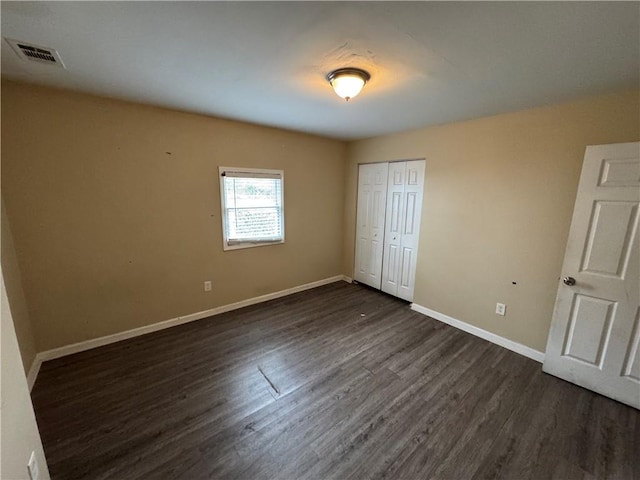 unfurnished bedroom featuring dark hardwood / wood-style flooring and a closet