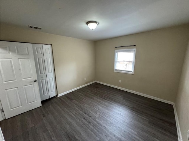 unfurnished bedroom featuring dark hardwood / wood-style flooring and a closet