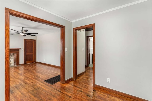 spare room featuring baseboards, wood finished floors, visible vents, and ornamental molding