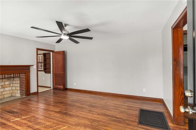 unfurnished living room featuring wood finished floors, baseboards, visible vents, a fireplace, and ceiling fan