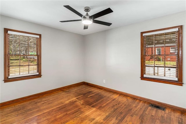 unfurnished room featuring visible vents, plenty of natural light, baseboards, and hardwood / wood-style flooring