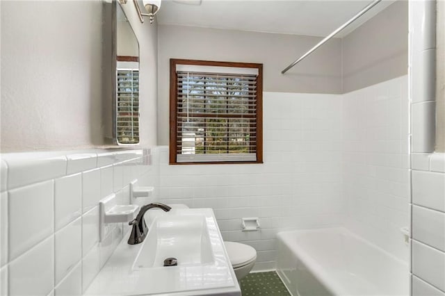 full bathroom featuring toilet, tile walls, bathing tub / shower combination, and a sink