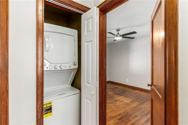 washroom featuring baseboards, stacked washer and dryer, laundry area, wood finished floors, and a ceiling fan