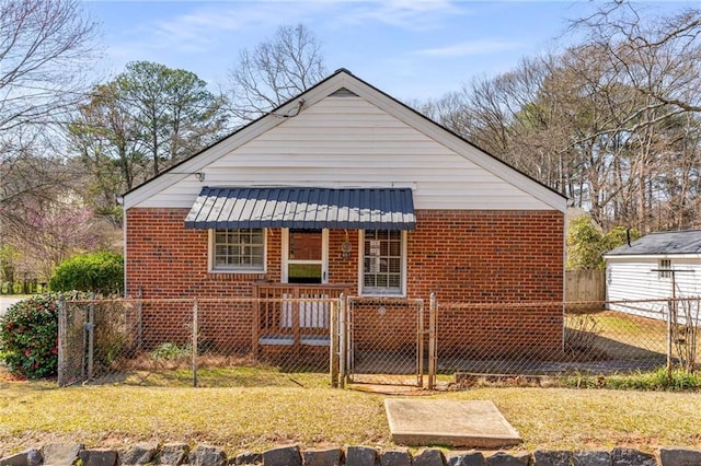 view of front facade with brick siding, fence, a front lawn, and a gate