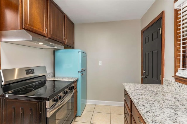 kitchen featuring light stone countertops, baseboards, light tile patterned flooring, stainless steel range with electric cooktop, and under cabinet range hood