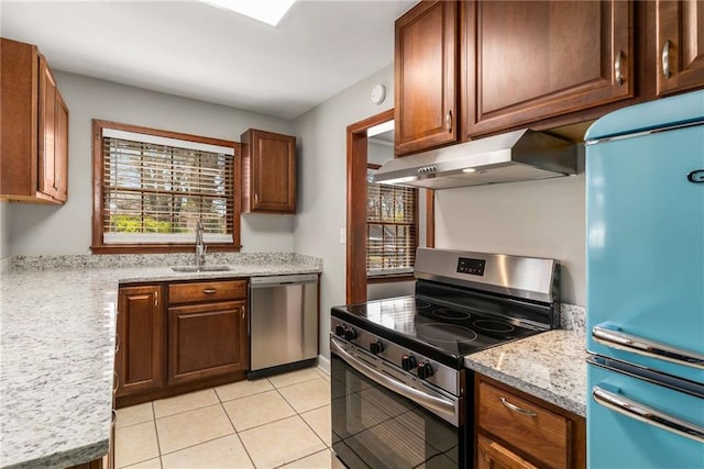 kitchen featuring light stone counters, light tile patterned floors, a sink, stainless steel appliances, and under cabinet range hood