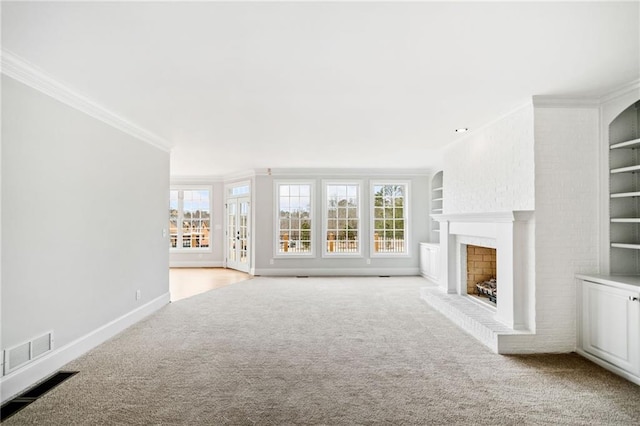 unfurnished living room featuring built in features, ornamental molding, a brick fireplace, and light carpet