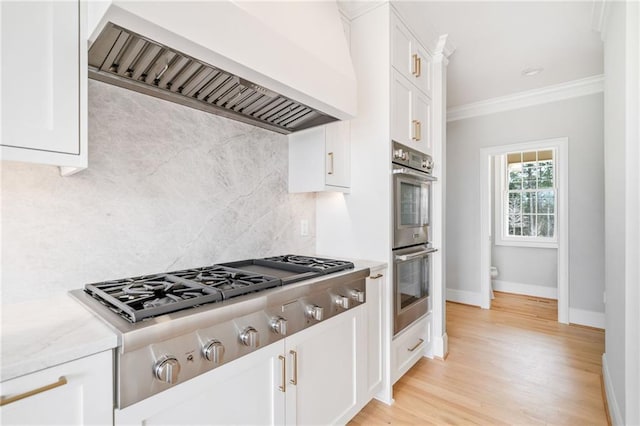 kitchen with premium range hood, stainless steel appliances, crown molding, and white cabinets