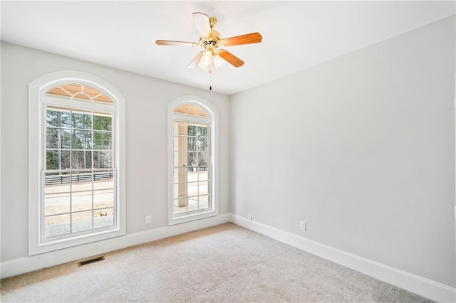 carpeted empty room featuring a wealth of natural light and ceiling fan