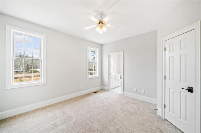 unfurnished bedroom with ceiling fan, ensuite bath, and carpet floors