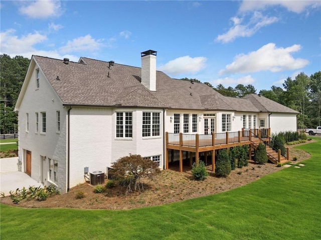 back of house featuring a garage, central AC unit, a deck, and a lawn