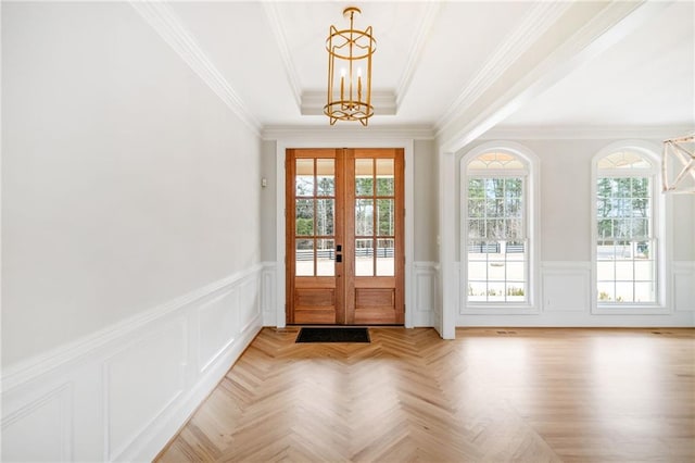 doorway to outside with crown molding, a notable chandelier, a tray ceiling, light parquet flooring, and french doors