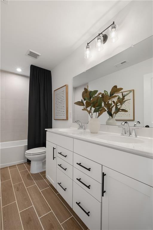 full bathroom with vanity, shower / bathtub combination with curtain, and toilet