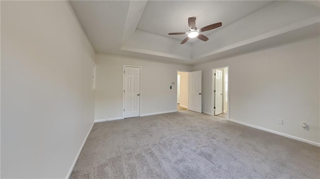 empty room featuring light colored carpet, a raised ceiling, and ceiling fan