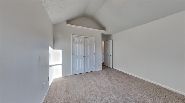 unfurnished bedroom featuring lofted ceiling, light carpet, a textured ceiling, and a closet