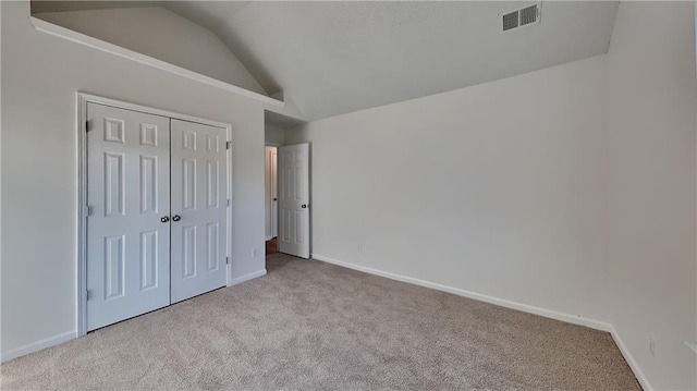 unfurnished bedroom featuring light colored carpet, vaulted ceiling, and a closet