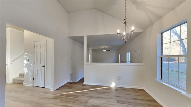 spare room featuring high vaulted ceiling, an inviting chandelier, and light wood-type flooring