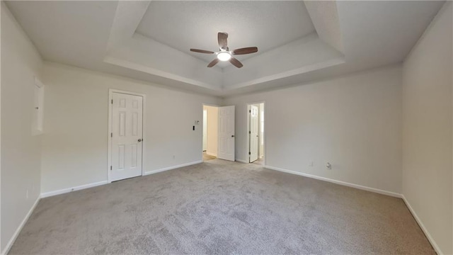 unfurnished room with light carpet, ceiling fan, and a tray ceiling