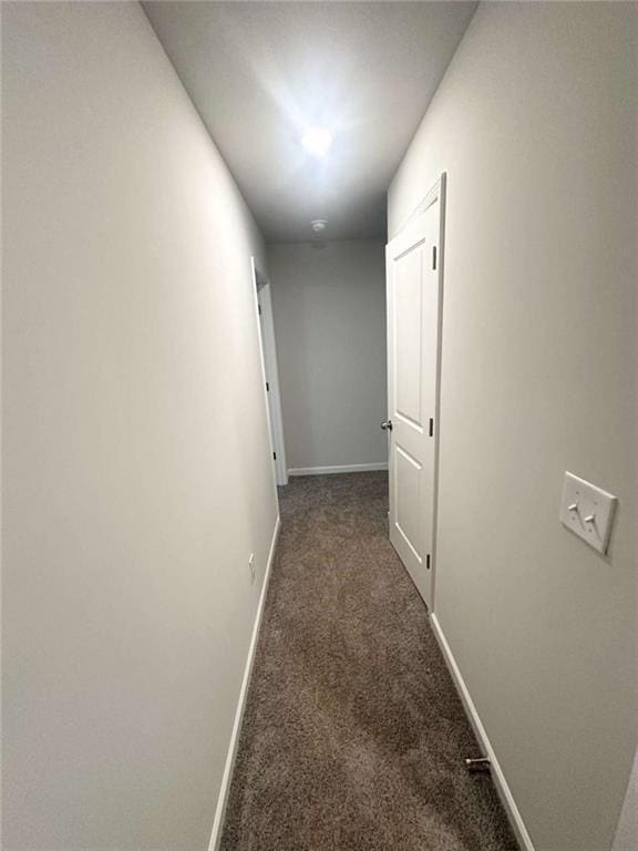 hallway with baseboards and dark carpet