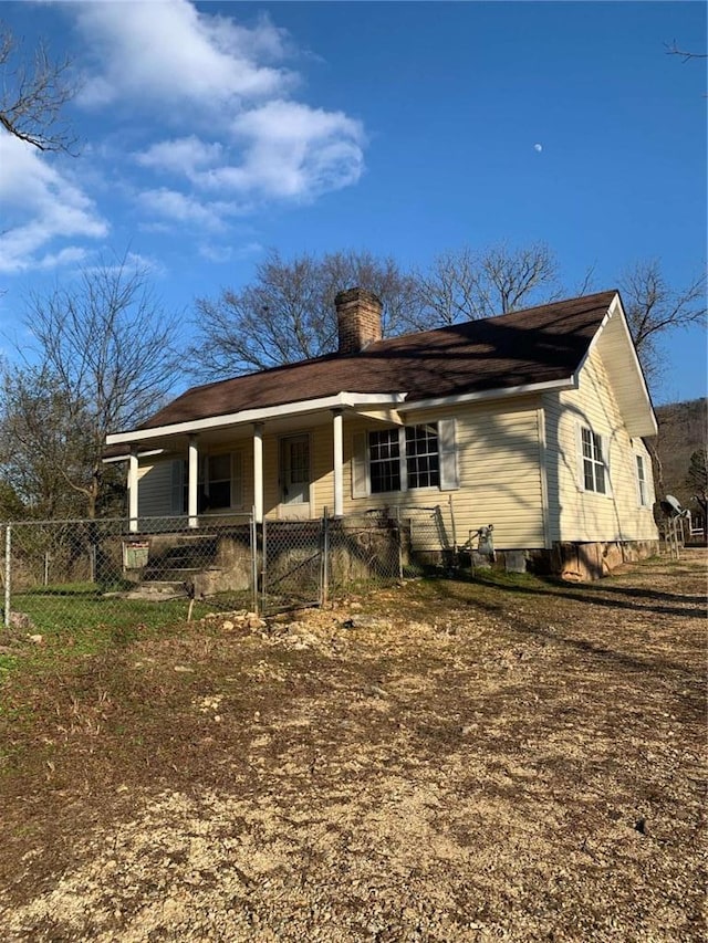 back of house featuring a gate, a chimney, and fence