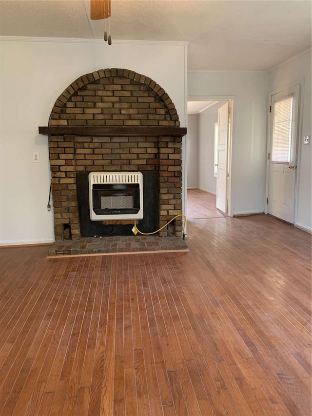 unfurnished living room featuring heating unit, a brick fireplace, and wood finished floors