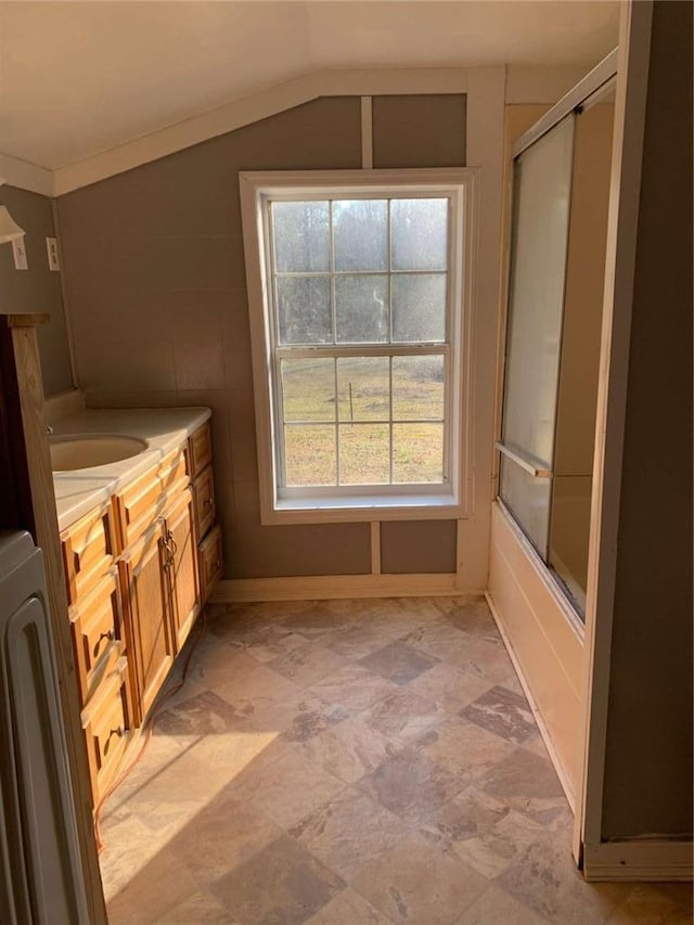 bathroom with vanity, vaulted ceiling, washer / clothes dryer, and combined bath / shower with glass door