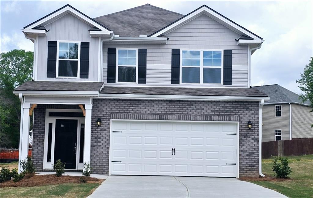 traditional-style house with a front yard, brick siding, driveway, and an attached garage