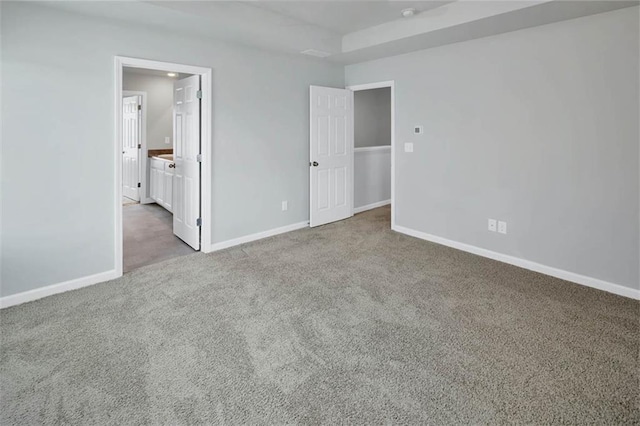 unfurnished bedroom featuring carpet floors, ensuite bath, and baseboards