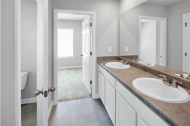 bathroom with double vanity, baseboards, and a sink