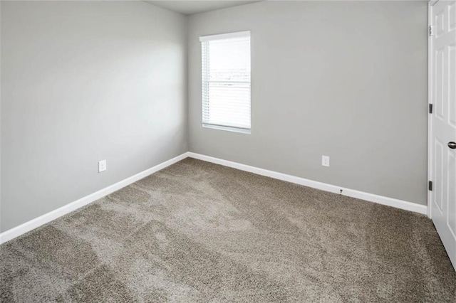empty room featuring carpet and baseboards