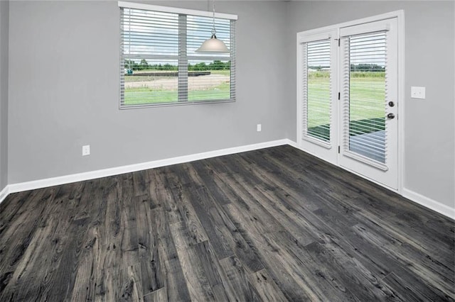 unfurnished dining area featuring dark wood finished floors and baseboards