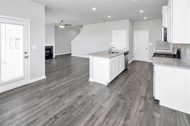 kitchen with appliances with stainless steel finishes, white cabinets, a sink, and a glass covered fireplace