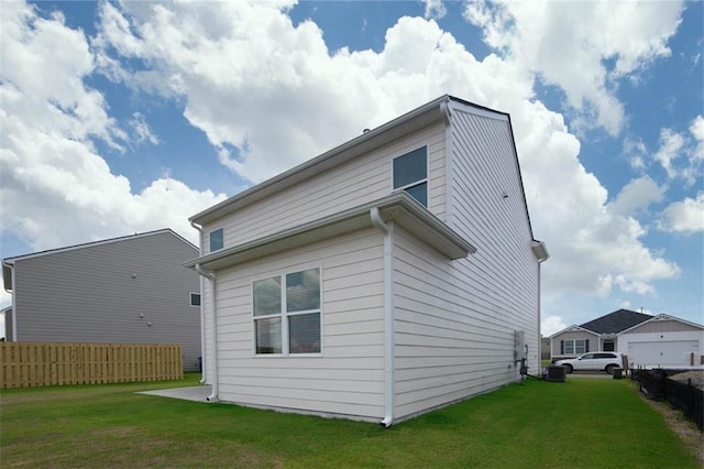 view of home's exterior featuring a lawn and fence