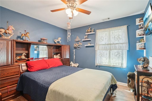 bedroom featuring wood finished floors, baseboards, and a ceiling fan