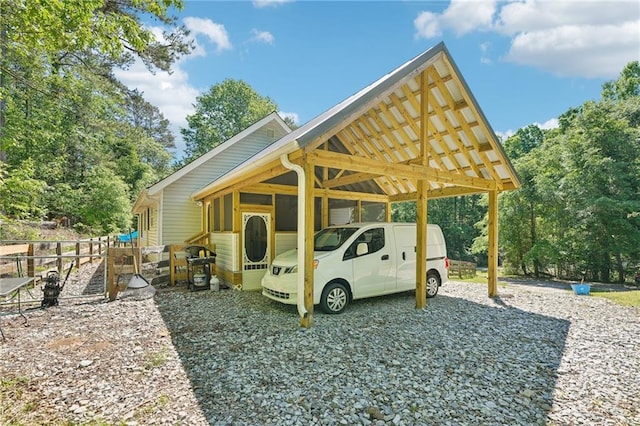 view of car parking with a carport, gravel driveway, and fence