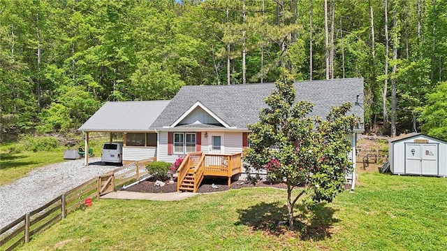 view of front facade with a storage unit, a shingled roof, an outdoor structure, a wooded view, and driveway