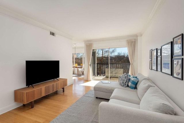 living room featuring visible vents, baseboards, light wood-style flooring, and crown molding