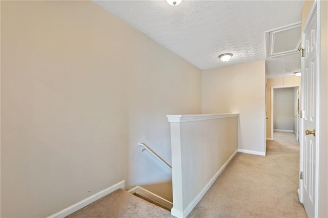 corridor with light carpet and a textured ceiling